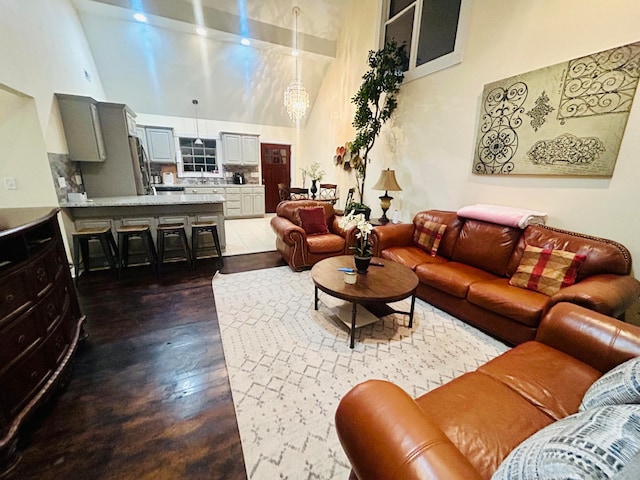 living room featuring a towering ceiling, a chandelier, and dark hardwood / wood-style floors