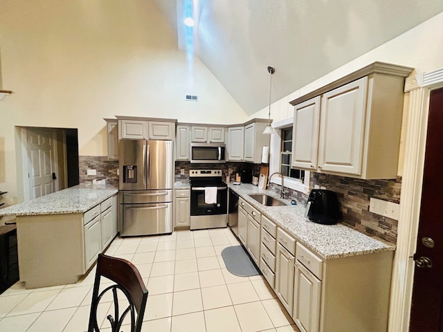 kitchen featuring light stone countertops, appliances with stainless steel finishes, sink, high vaulted ceiling, and hanging light fixtures