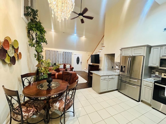 kitchen with gray cabinetry, a towering ceiling, and stainless steel appliances