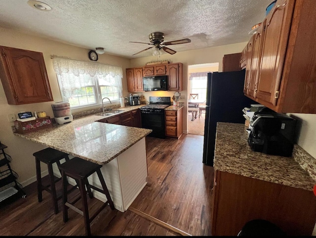 kitchen with black appliances, plenty of natural light, kitchen peninsula, and sink