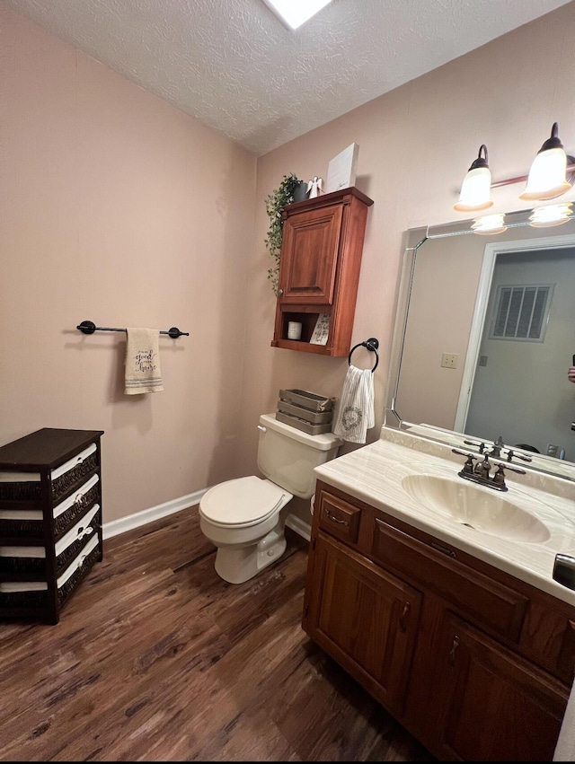 bathroom with vanity, wood-type flooring, a textured ceiling, and toilet