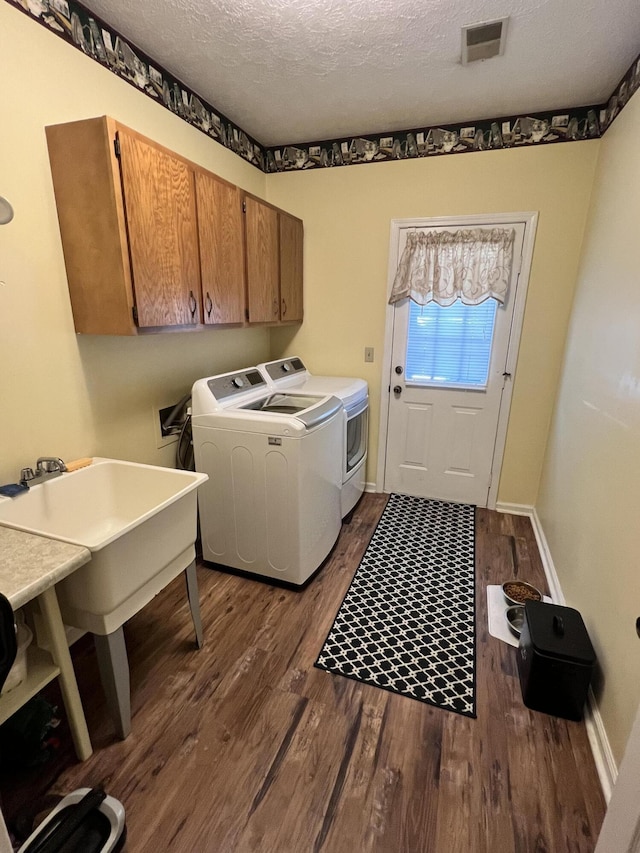 washroom with dark hardwood / wood-style floors, cabinets, independent washer and dryer, and a textured ceiling