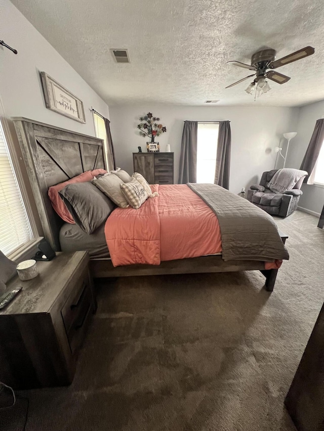 carpeted bedroom with ceiling fan and a textured ceiling