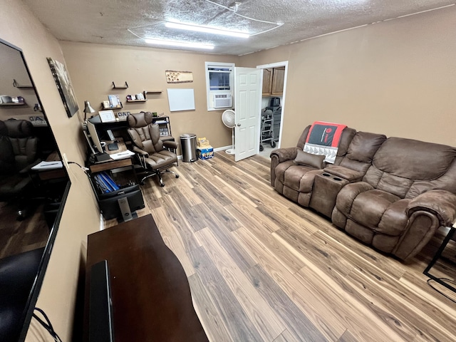 living room with cooling unit, wood-type flooring, and a textured ceiling