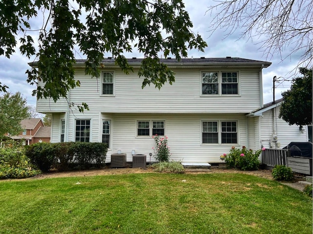 rear view of property with central AC and a yard