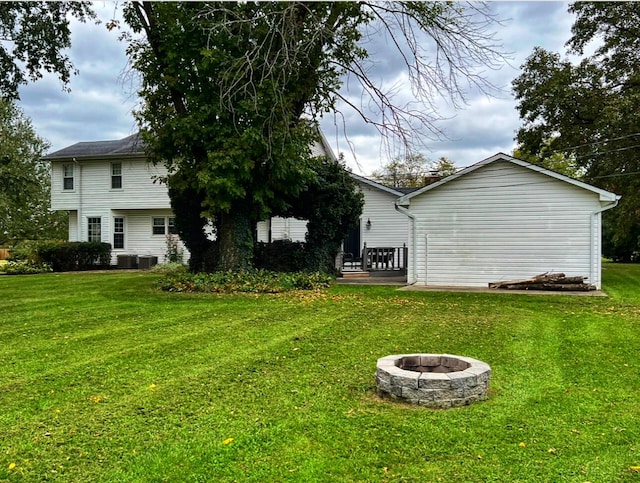 rear view of house featuring a fire pit, a yard, and central air condition unit