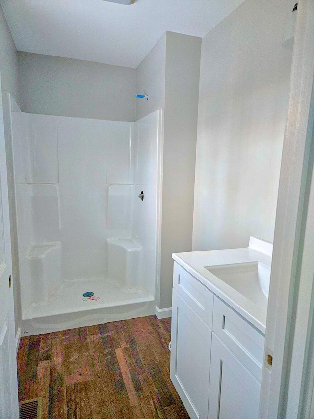 bathroom with hardwood / wood-style floors, a shower, and vanity