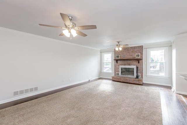 unfurnished living room featuring crown molding, a wealth of natural light, and a brick fireplace