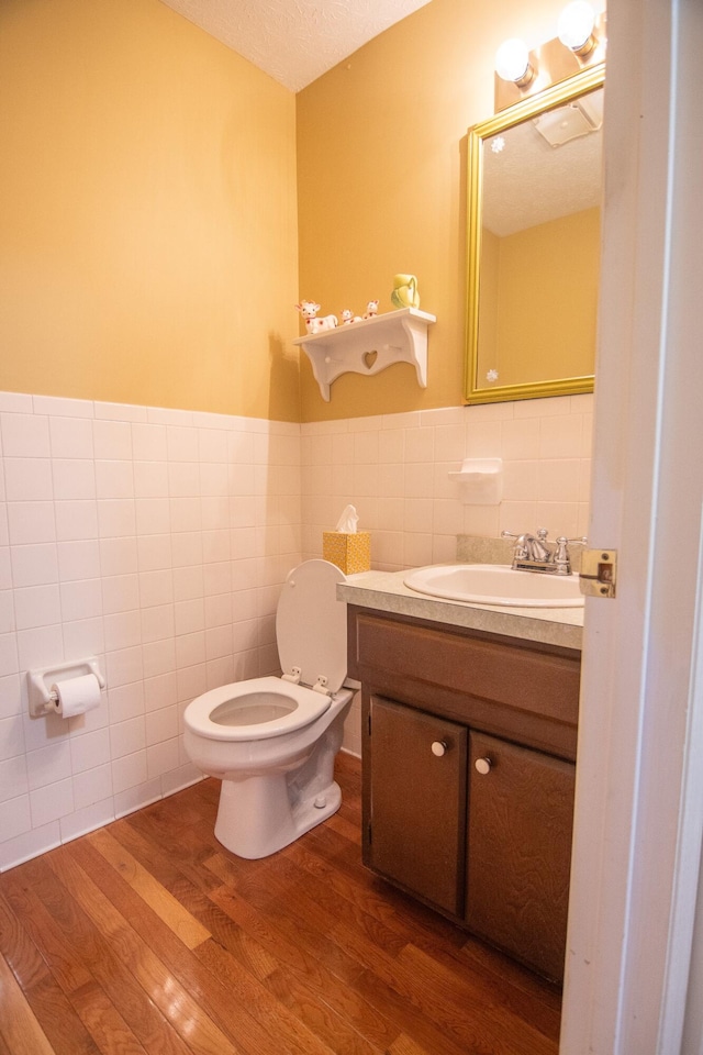 bathroom featuring toilet, tile walls, hardwood / wood-style floors, a textured ceiling, and vanity