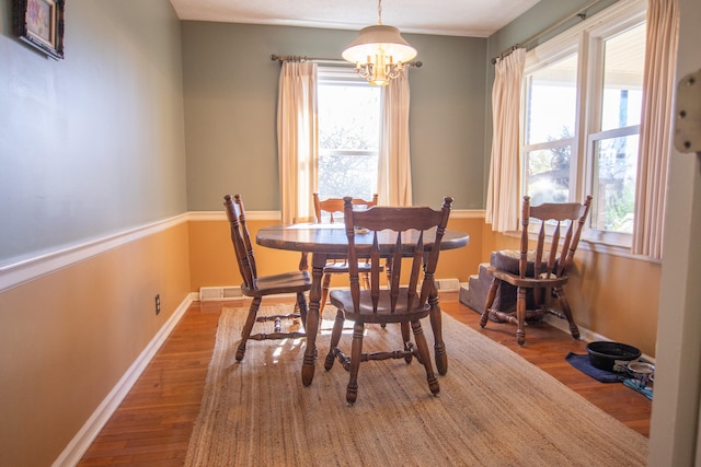 dining space featuring a wealth of natural light, a notable chandelier, and hardwood / wood-style flooring