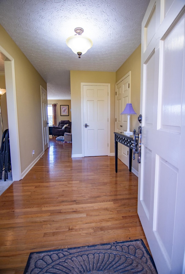 hallway with hardwood / wood-style flooring and a textured ceiling