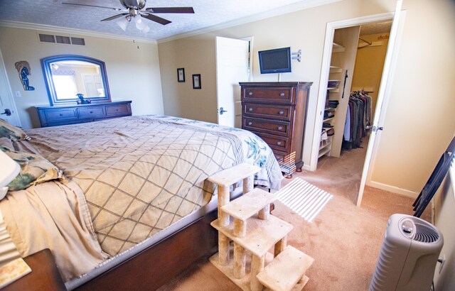 bedroom featuring ceiling fan, crown molding, a closet, and a walk in closet