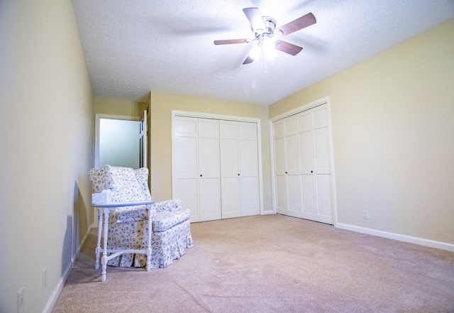 unfurnished room featuring a textured ceiling, light carpet, and ceiling fan