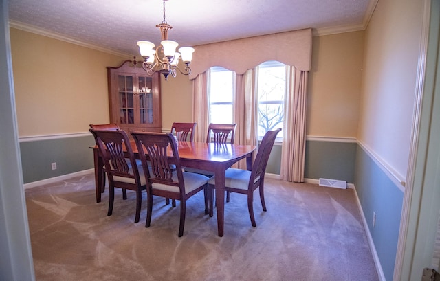 carpeted dining space with ornamental molding, a textured ceiling, and a chandelier