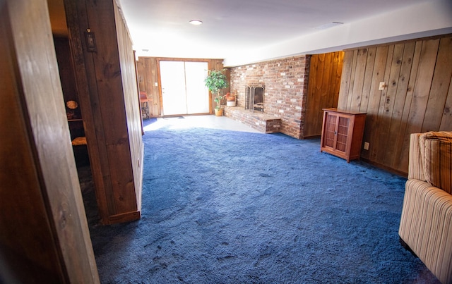 carpeted living room with a brick fireplace, wooden walls, and vaulted ceiling