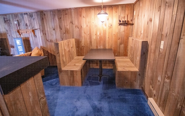 dining space with a baseboard radiator, wood walls, and dark carpet