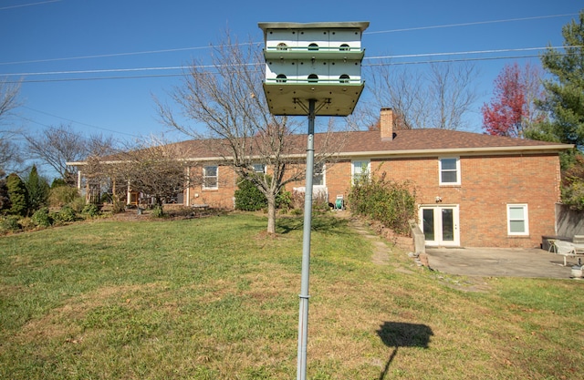 rear view of house with a lawn and a patio