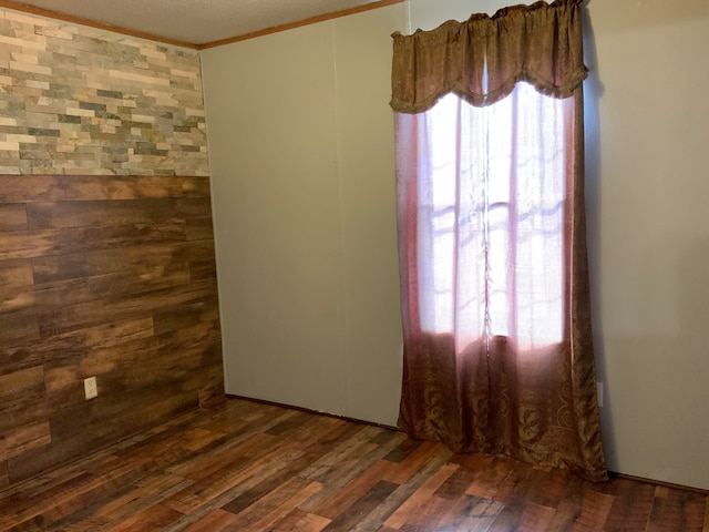 spare room with dark hardwood / wood-style flooring and crown molding