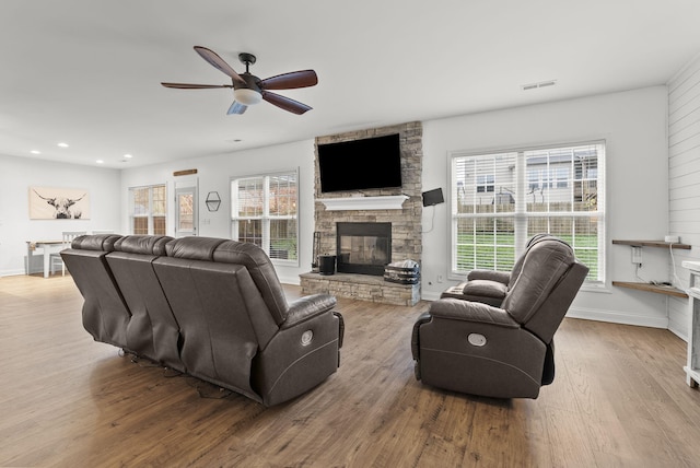 living room featuring light wood-type flooring, ceiling fan, a healthy amount of sunlight, and a fireplace