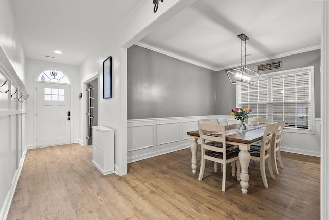 dining space featuring ornamental molding, a notable chandelier, and hardwood / wood-style flooring