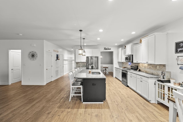 kitchen featuring white cabinetry, appliances with stainless steel finishes, a center island with sink, and sink