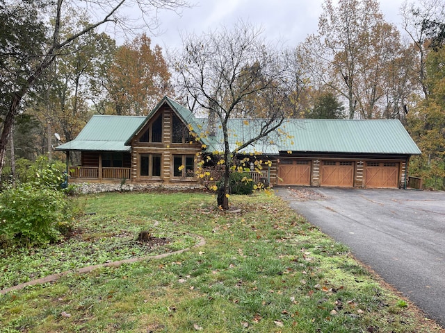 log cabin featuring covered porch, a garage, and a front lawn