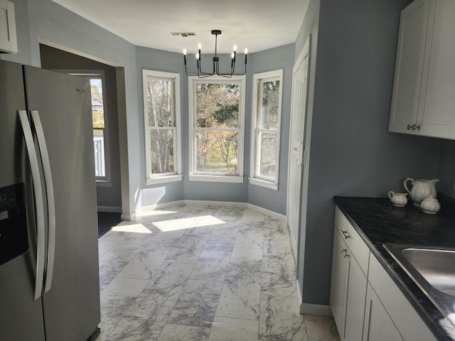 kitchen with white cabinetry, stainless steel refrigerator with ice dispenser, hanging light fixtures, and a notable chandelier