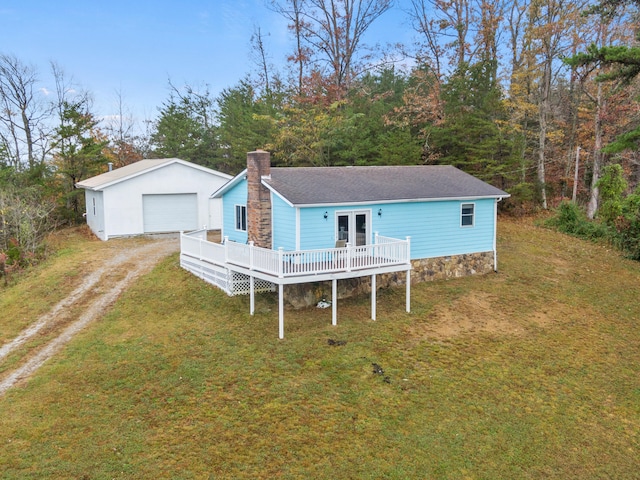 back of property featuring an outdoor structure, a deck, a garage, and a lawn