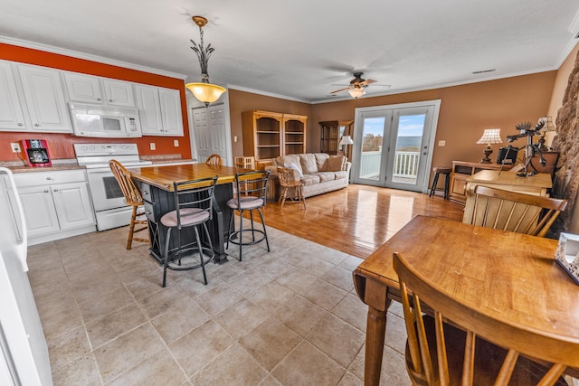 kitchen featuring white cabinets, ceiling fan, pendant lighting, crown molding, and white appliances