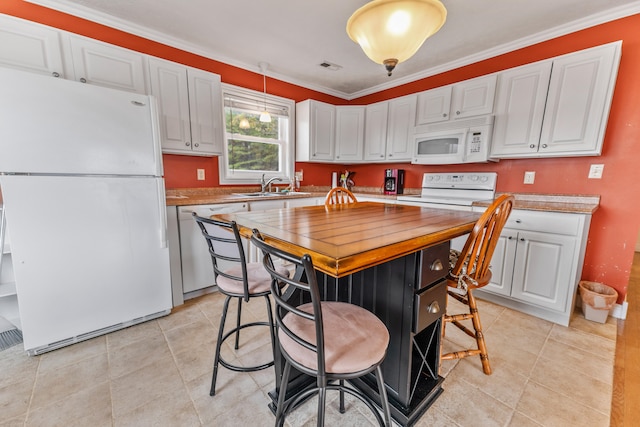 kitchen with white cabinetry, ornamental molding, sink, a center island, and white appliances