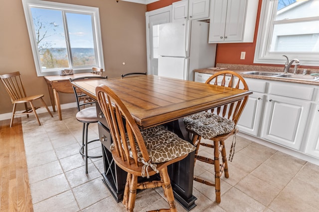 dining room featuring sink, light hardwood / wood-style flooring, and a healthy amount of sunlight