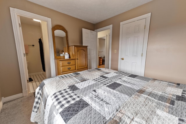 bedroom featuring light carpet, a closet, a textured ceiling, and ensuite bath