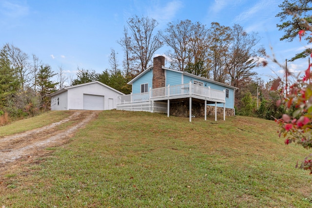 rear view of property featuring an outdoor structure, a wooden deck, a garage, and a lawn