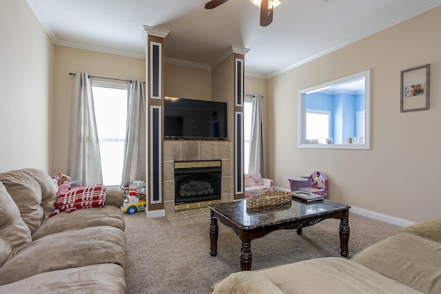 carpeted living room with ceiling fan, a tile fireplace, and crown molding