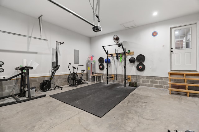 exercise room featuring electric panel, concrete floors, and electric water heater