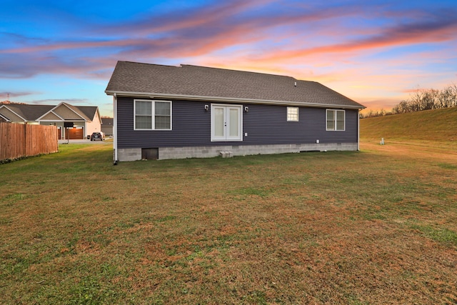 back house at dusk with a lawn