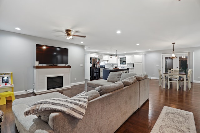 living room with dark wood-type flooring and ceiling fan