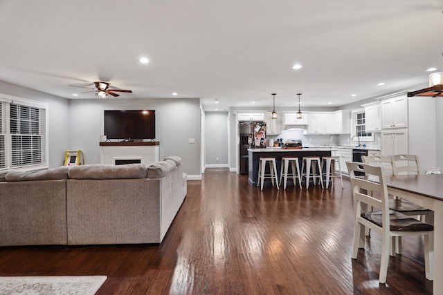 living room featuring ceiling fan, dark hardwood / wood-style floors, and sink