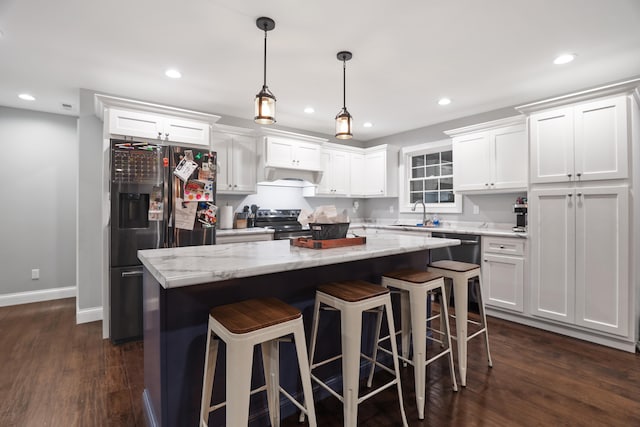 kitchen with a kitchen island, appliances with stainless steel finishes, dark hardwood / wood-style floors, pendant lighting, and white cabinets