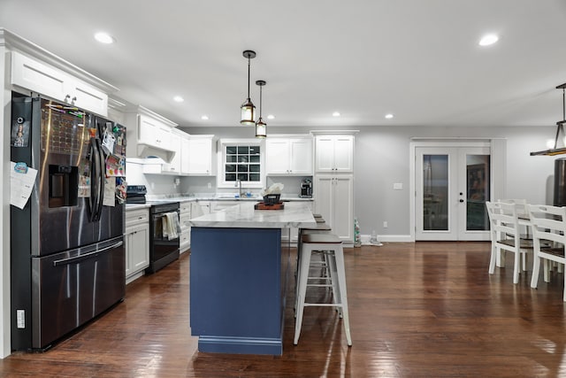 kitchen featuring black electric range, stainless steel refrigerator with ice dispenser, hanging light fixtures, and a kitchen island