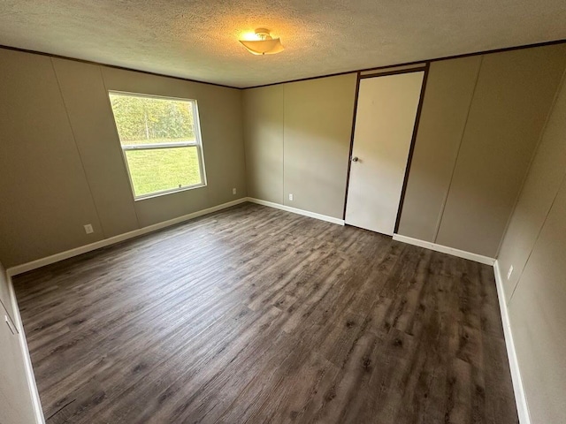 unfurnished bedroom with a textured ceiling and dark hardwood / wood-style flooring