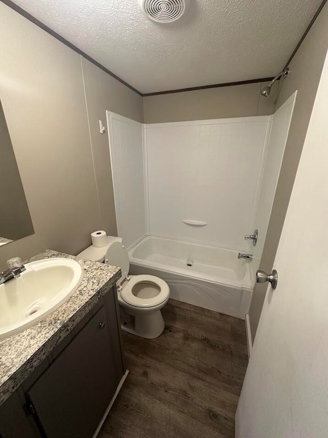 full bathroom with vanity, a textured ceiling, bathtub / shower combination, hardwood / wood-style flooring, and toilet