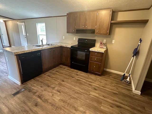 kitchen featuring dark hardwood / wood-style floors, sink, black appliances, and kitchen peninsula