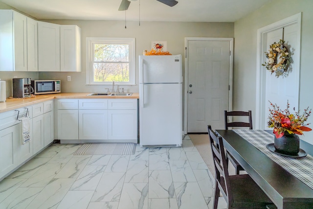 kitchen featuring white cabinetry, white refrigerator, sink, and ceiling fan