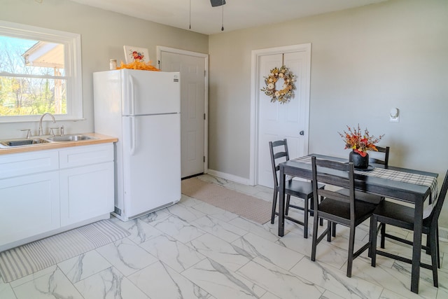 kitchen featuring sink, white fridge, and white cabinets