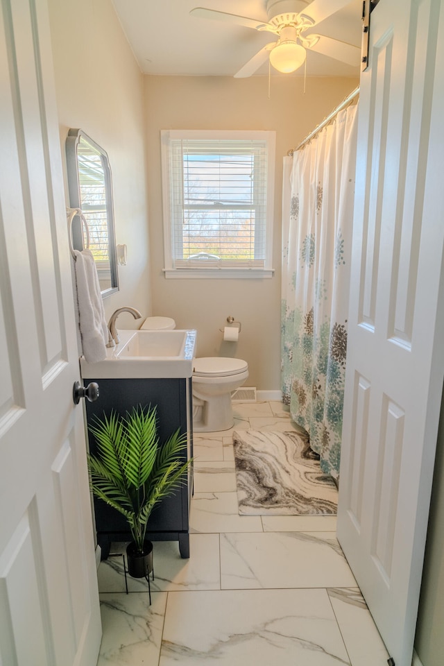 bathroom featuring vanity, ceiling fan, a healthy amount of sunlight, and toilet