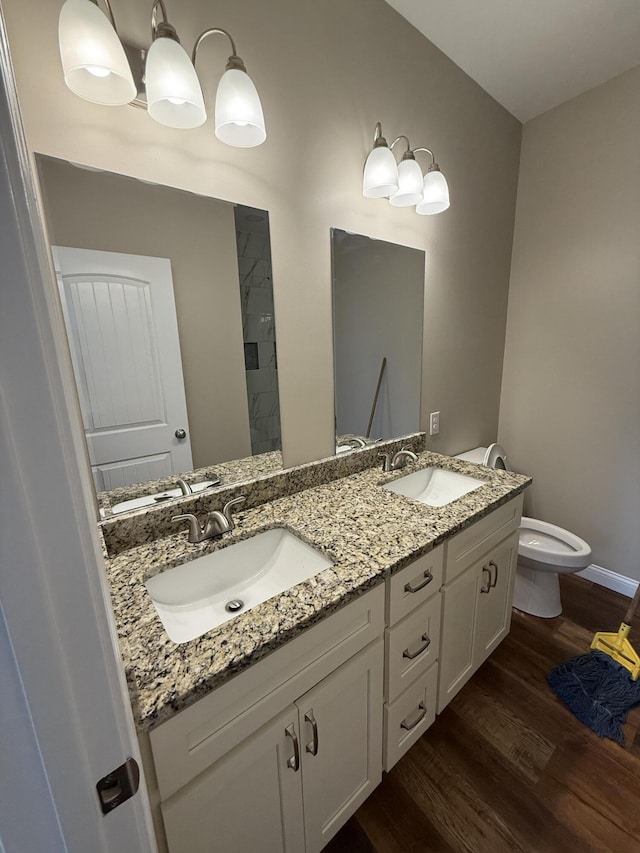 bathroom with a sink, toilet, wood finished floors, and double vanity