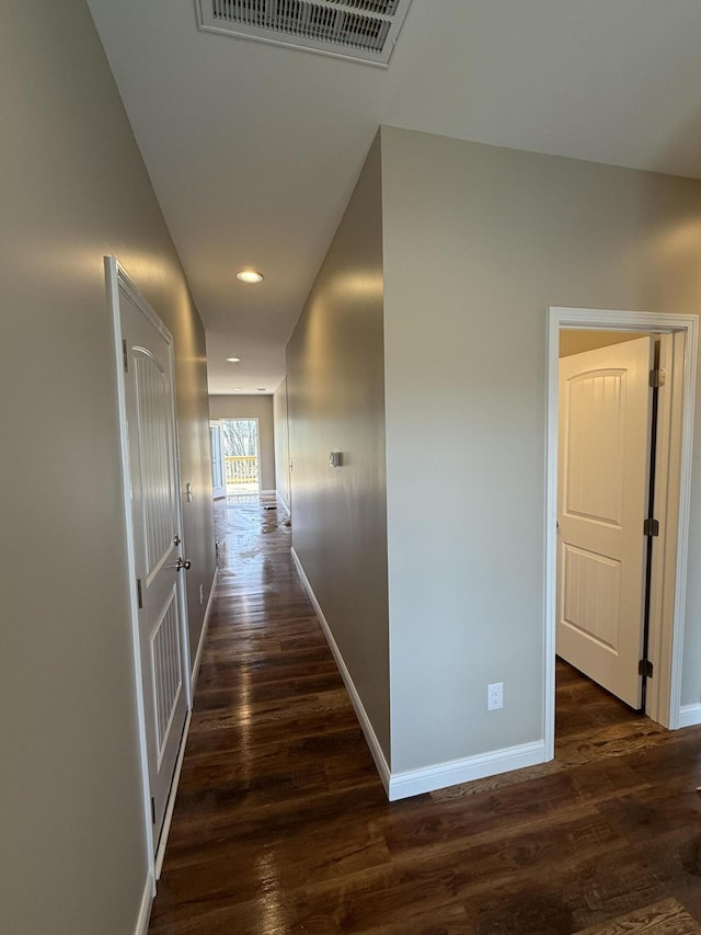 corridor featuring visible vents, dark wood-type flooring, and baseboards