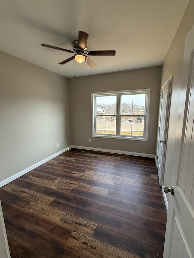 spare room featuring ceiling fan, baseboards, and dark wood finished floors