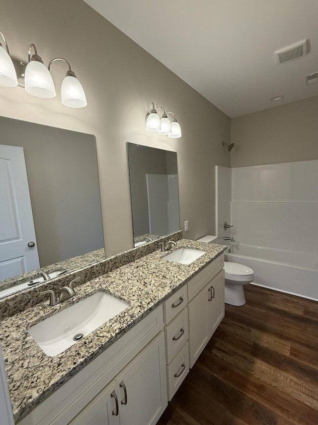 bathroom with visible vents, toilet, wood finished floors, and a sink